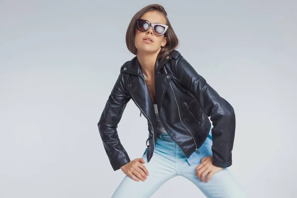 Charmantes Model Posiert Mit Lederjacke Und Sonnenbrille Auf Grauem Studiohintergrund — Stockfoto