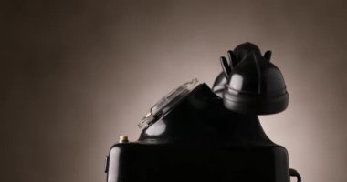 Kahverengi arka planda dönen ve dönen eski siyah telefonun yan görünümü