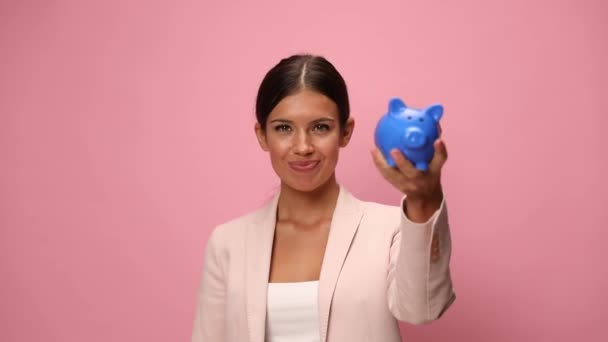 Glad Ung Kvinna Rosa Kostym Hålla Spargris Bank Och Peka — Stockvideo