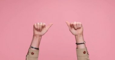 two hands pointing at the camera, giving a thumbs up on pink background