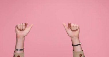 two hands showing palms, pointing at the camera, giving a thumbs up, clapping on pink background
