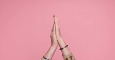 two hands clapping, pointing at the camera, giving a thumbs up on pink background