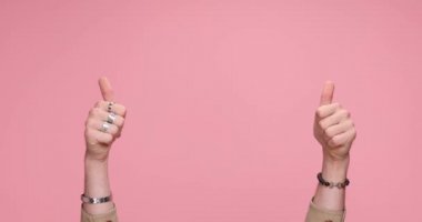 two hands showing palms, giving a thumbs up, celebrating succes, clapping on pink background