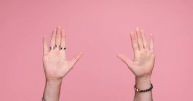 two hands gesturing hey you, give me five and you suck on pink background