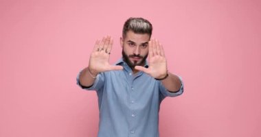 Pembe arka plana karşı mükemmel çerçeveyi elde etmeye odaklanan sıradan bir genç.