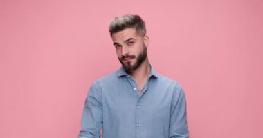cool casual guy gesturing a gun, shooting at the camera then blowing the smoke and pointing it at his head against pink background