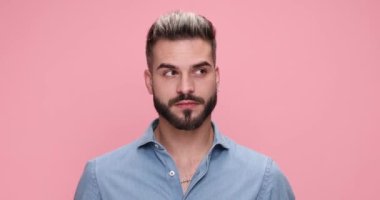 Yakışıklı, sıradan bir adam etrafına bakıyor sonra ağzını açıp pembe arka planda işaretini kesiyor.