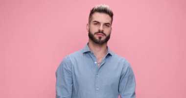 young casual man pointing at the camer and expanding his smile, giving a thumbs up on pink background