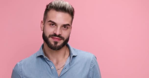 魅力的なカジュアルな男がトロフィーを掲げピンクの背景に親指を上げ — ストック動画