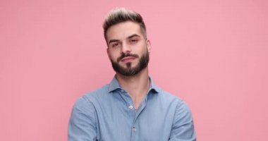 young sexy casual man laughing, winking and flirting on pink background