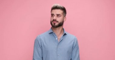 Genç, çekici, sıradan bir adam etrafına bakıyor sonra kameraya bakıyor ve pembe arka planda kahkahalarla gülüyor.