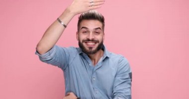 young casual man switching from surprised face to a serious one, happy, crazy, goofy, disgusted and finally serious again on pink background