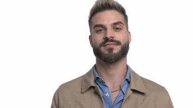 Çekici, sıradan bir adam gülümsüyor, bej ceketi temizliyor ve el hareketi yapıyor. Stüdyoda beyaz arka planda tek başına kalıyor.