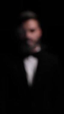 Gizemli genç modelin dikey portresi. Tarafsız ve dumanlı görünüyor, duygusal olarak omuzlarının üzerinden bakıyor ve stüdyodaki siyah arka planda kalıyor.