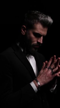 Dramatik genç modelin dikey portresi çapraz ve dokunaklı parmaklar, aşağı bakıyor ve düşünüyor, duruyor ve poz stüdyoda siyah arka plan üzerinde moda ışığı