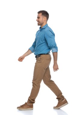 Genç, sıradan bir adam, beyaz arka plana karşı çok iyi bir ruh hali içinde kendi yolunda yürüyor.