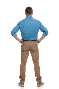 Elleri kalçasının üzerinde duran ve beyaz arka planda bir durum hakkında kafa yoran sıradan bir adamın arka planı.