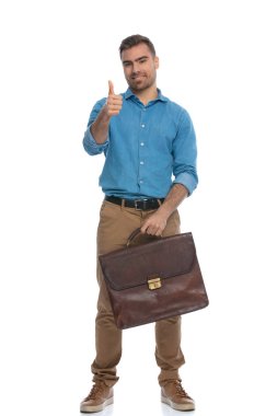 Elinde evrak çantası olan yakışıklı, sıradan bir adam beyaz arka plana başparmak işareti yapıyor.