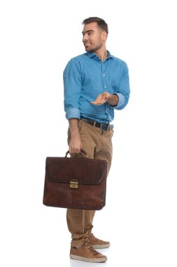 Genç, sıradan bir adam ne istediğini söylüyor. Omuzlarının üzerinden geriye bakıyor ve beyaz arka plana karşı bir evrak çantası tutuyor.