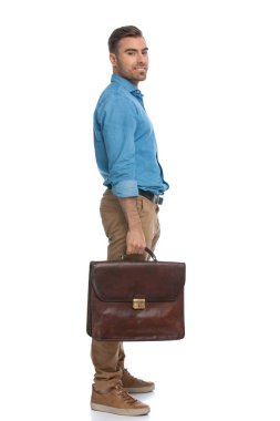 Evrak çantasını tutan ve beyaz arka planda kameraya gülümseyen mutlu bir adamın yan görüntüsü.