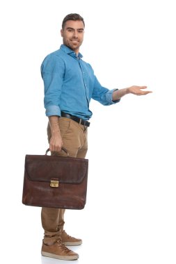 Elinde evrak çantası olan yakışıklı bir adam beyaz arka plana karşı bir tarafı işaret ediyor.