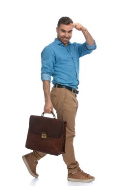 Elinde evrak çantasıyla yürüyen ve beyaz arka planda kameraya bakan çekici, sıradan bir adam.