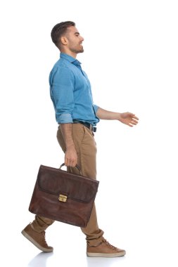 Beyaz arka plandan korkmadan yürüyen sıradan bir gencin yan görüntüsü.