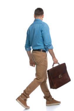 Evrak çantasını beyaz arka planda tutarken diğer tarafa bakan sıradan bir adamın arkadan görünüşü.