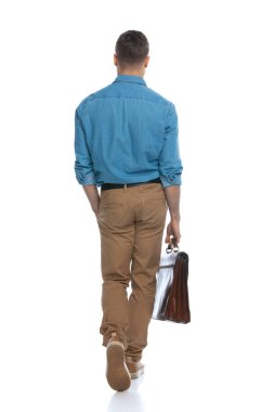 Bir eli cebinde ve beyaz arka planda bir evrak çantasıyla kameradan uzaklaşan sıradan bir adamın arka görüntüsü.