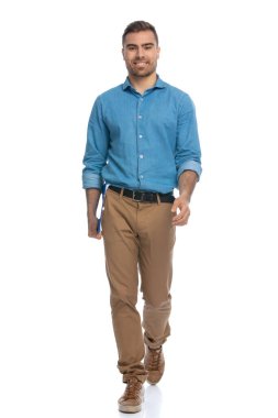 Yakışıklı, sıradan bir adam elinde mavi bir panoyla kameraya doğru yürüyor ve beyaz arka plana gülümsüyor.