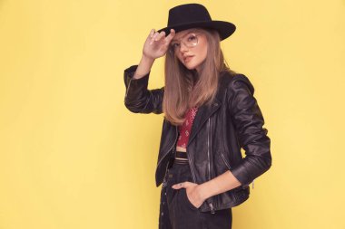 Çekici bir manken bir eli havada, diğeri de sarı arka planda poz veriyor.