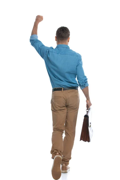 一个普通男人一边走着一边拿着一个白色背景的公文包庆祝胜利的后视镜 — 图库照片