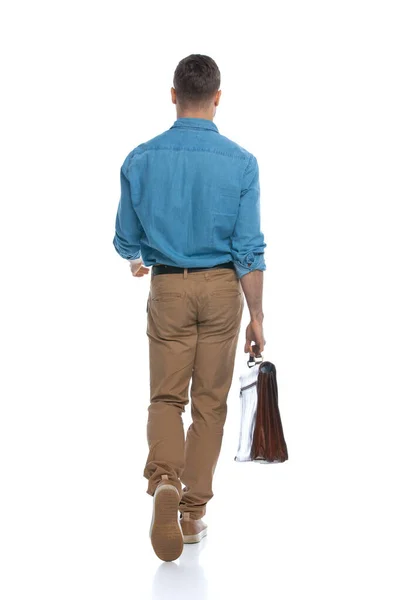 손에는 가방을 배경을 배경으로 걸어가는 남자의 뒷모습 — 스톡 사진