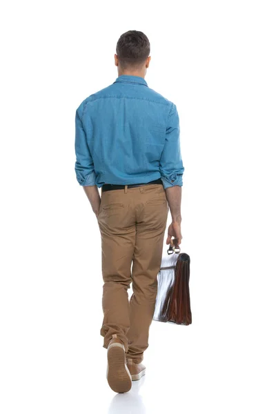 一个普通男子一只手插在口袋里 背着一个白色背景的公文包 从相机前走开的后视镜 — 图库照片