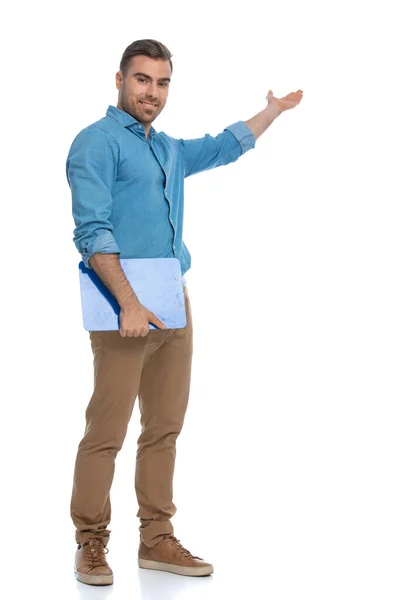 Pohledný Ležérní Muž Představuje Něco Drží Modrý Clipboard Proti Bílému — Stock fotografie