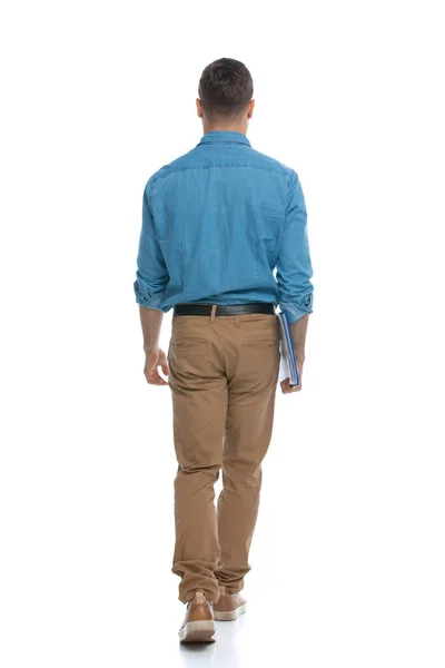 Bonito Casual Homem Caminhando Longe Câmera Segurando Azul Prancheta Contra — Fotografia de Stock