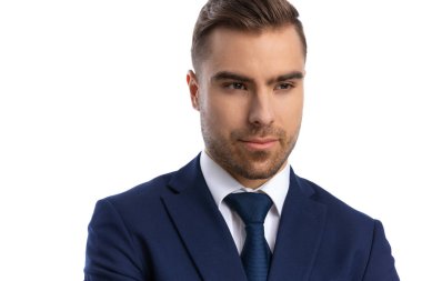 Stüdyoda beyaz arka planda tek başına dikilip poz veren lacivert takım elbiseli şık bir manken.