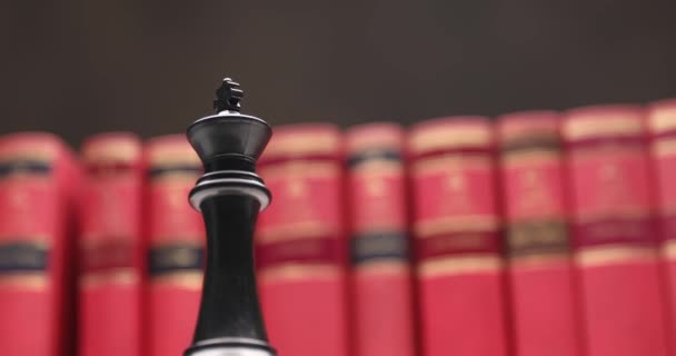 大学の部屋で左右に動く赤い本の前に黒い王とチェスの概念の製品ビデオ — ストック動画