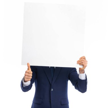 Lacivert takım elbiseli bir işadamının portresi. Başparmak hareketi yapıyor ve stüdyoda beyaz arka planda boş bir tahtanın arkasına saklanıyor.