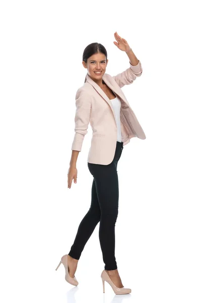 幸せな若いビジネスマン女性でピンクのジャケット笑顔 軍の敬礼とスタジオで白の背景に隔離された歩行 — ストック写真