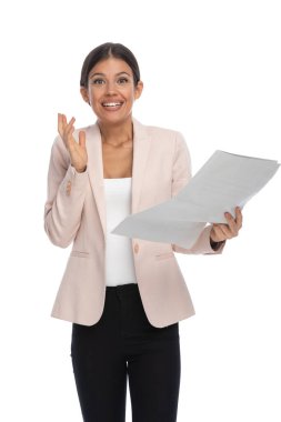 Pembe ceketli heyecanlı bir bayan gazete okuyor, şaşırmış bir şekilde gülümsüyor ve stüdyoda beyaz arka planda poz veriyor.