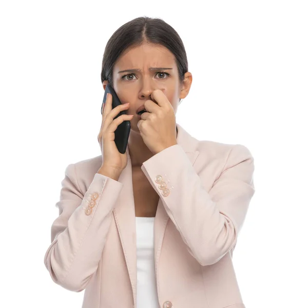 穿着粉色夹克的年轻女子吓坏了 她在电话里交谈 手牵着手 在工作室的白色背景下忧心忡忡 — 图库照片