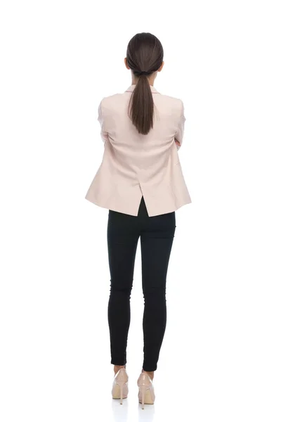 一个年轻的女商人的背影 她的马尾辫交叉着胳膊 站在工作室的白色背景上 — 图库照片
