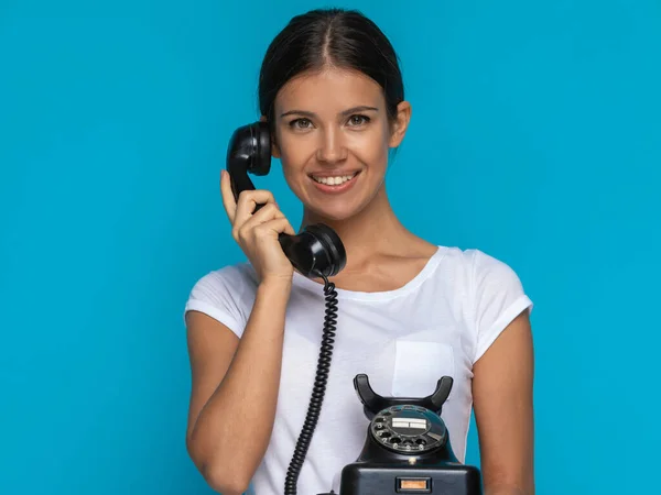 青を背景に古い電話で笑顔で話す美しいカジュアルな女性 — ストック写真