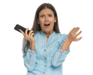 Güzel, sıradan bir kadın telefonda beyaz arka planda hayal kırıklığına uğruyor.