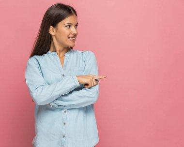 Seksi, sıradan bir kadın pembe arka plana bakıp onu işaret ediyor.