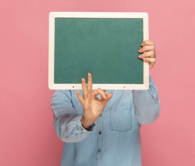 Sıradan bir kadın pembe arka planda yeşil bir panonun arkasında 