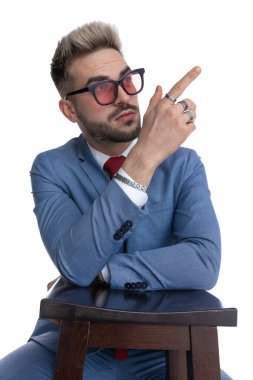 Oturmuş genç işadamı beyaz arka planda bir sandalyeye bakıyor ve dinleniyor.