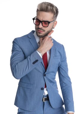 Seksi şehvetli iş adamı yüzüne dokunuyor ve beyaz arka plana bakıyor.