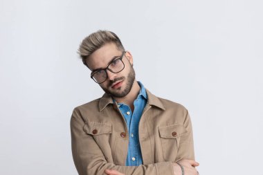 Kot gömlekli, gözlüklü, moda kollu, gri arka planda duran seksi bir adamın portresi.